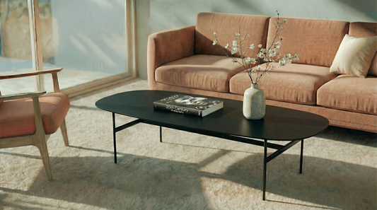 Minimalistische design salontafel met ovaal zwart tafelblad en slank metalen frame in moderne woonkamer| Minimalistischer Design-Couchtisch mit ovaler schwarzer Tischplatte und schlankem Metallgestell im modernen Wohnzimmer | Minimalist oval black coffee table with sleek metal frame in a modern living room|Mesa de centro minimalista de diseño con tablero ovalado negro y estructura metálica en salón moderno